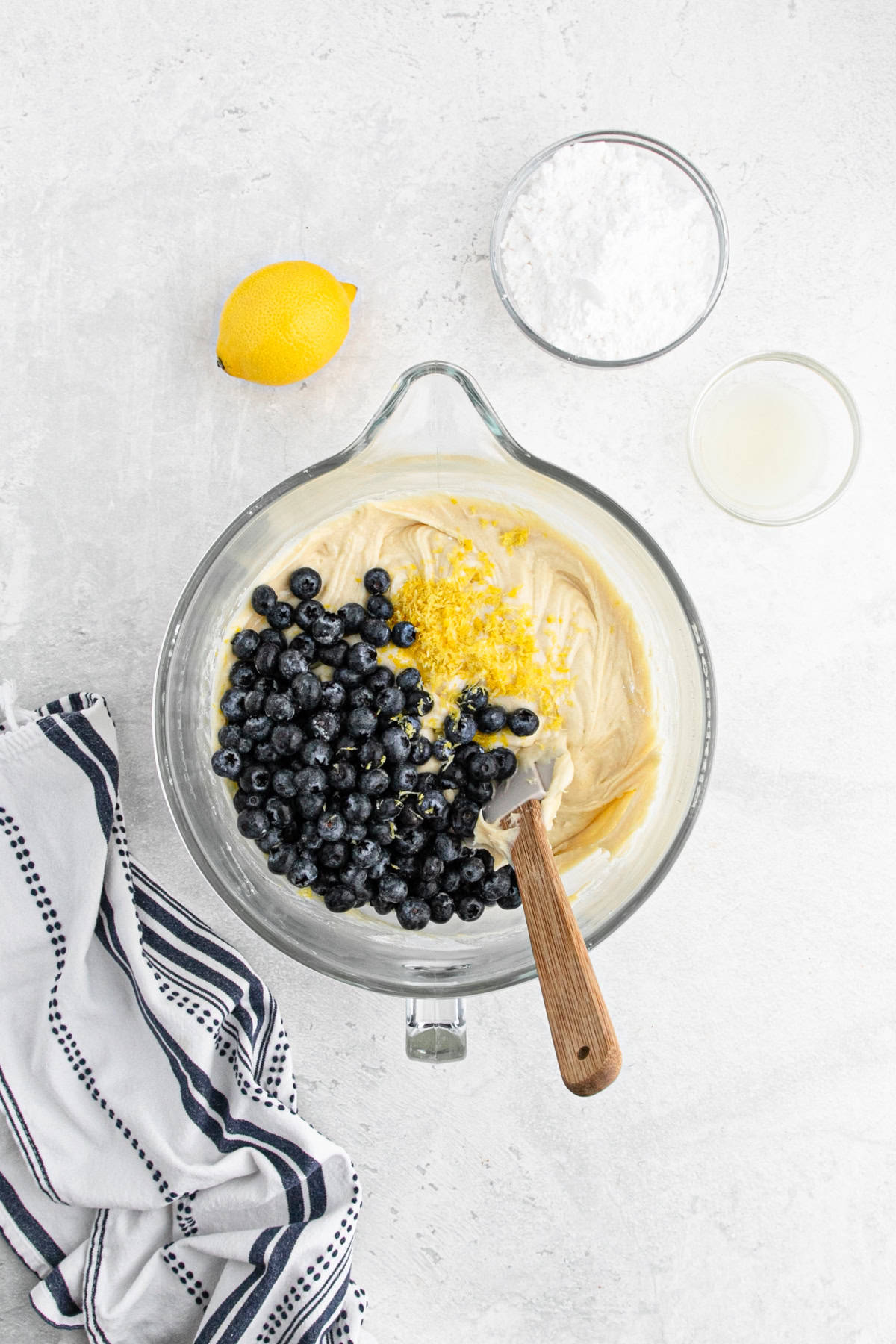 Cake batter with fresh blueberries and lemon zest being folded together