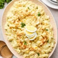 Southern potato salad in an oval serving plate with a wooden spoon near by