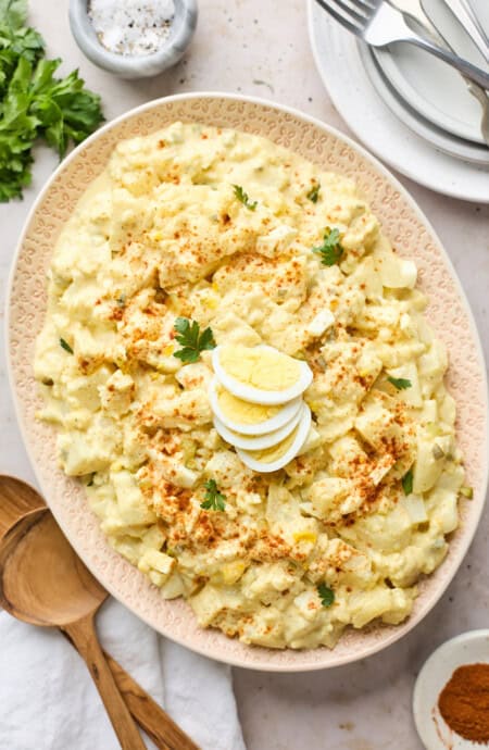 Southern potato salad in an oval serving plate with a wooden spoon near by