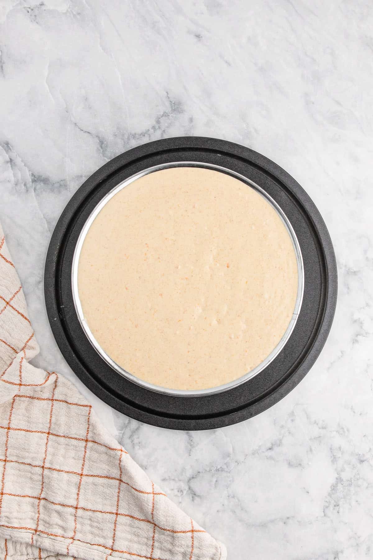 Unbaked spiced sweet potato cheesecake batter spread smoothly in a springform pan, ready to bake