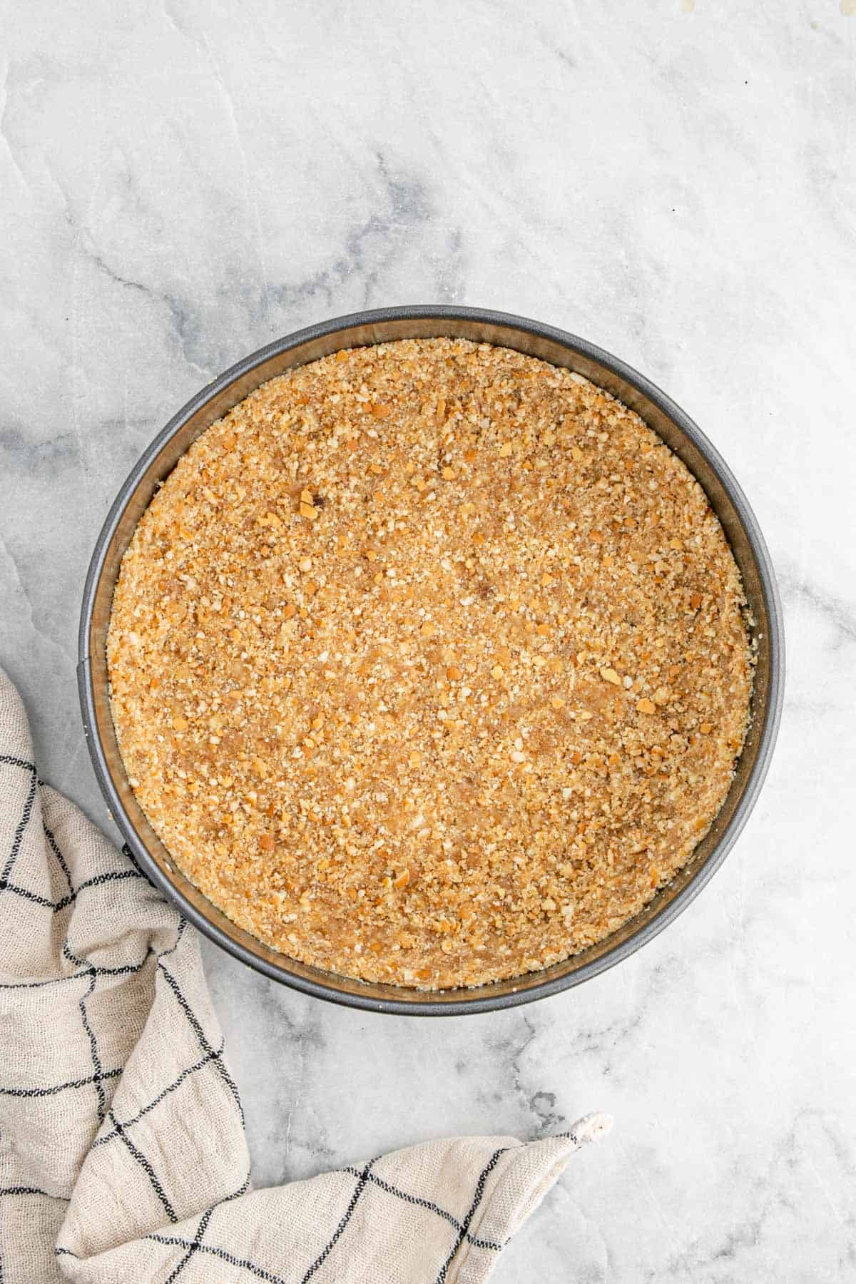 A springform pan filled with an even layer of crust, pressed and ready to be baked or chilled