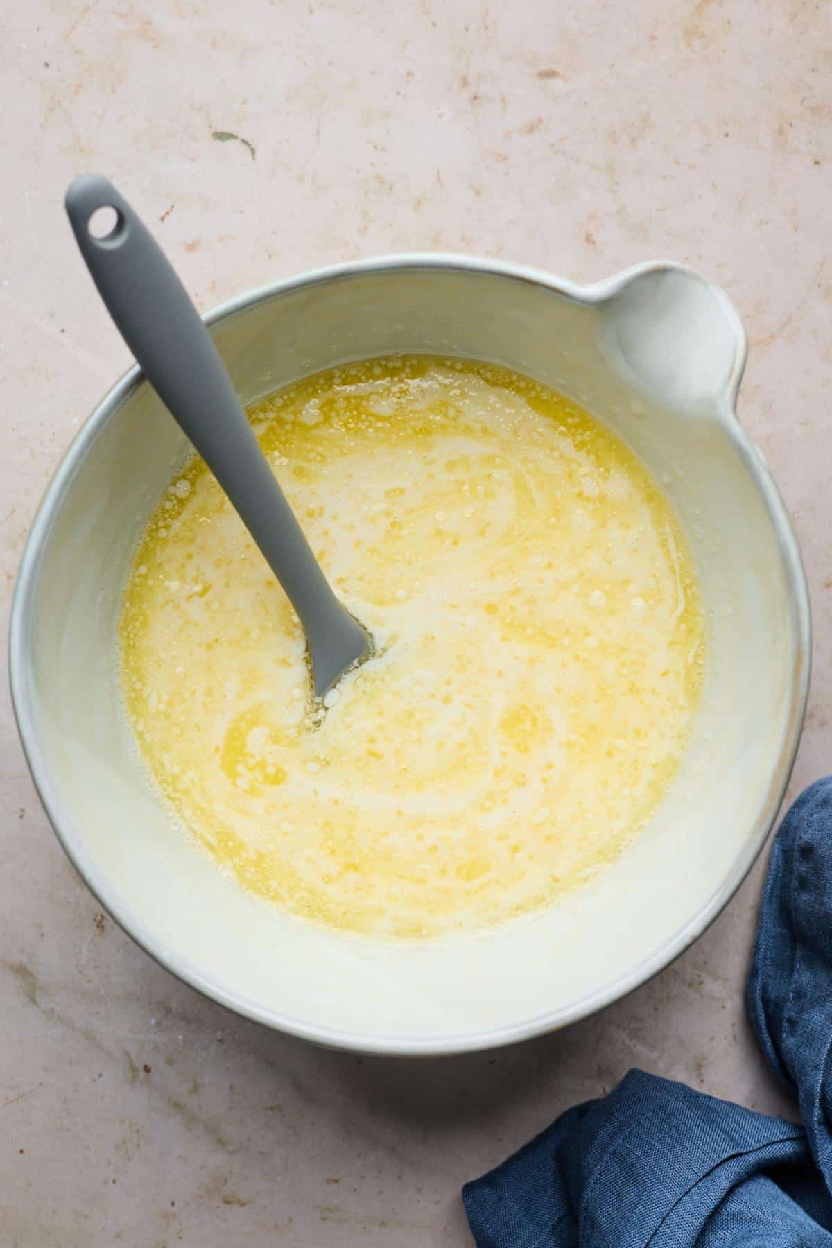 Wet ingredients mixed in bowl with a rubber spatula in it