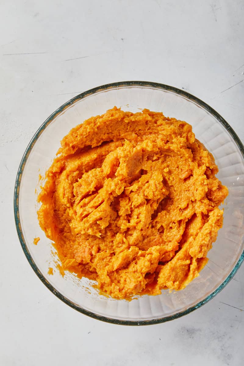 Mashed sweet potatoes in a glass bowl on gray background