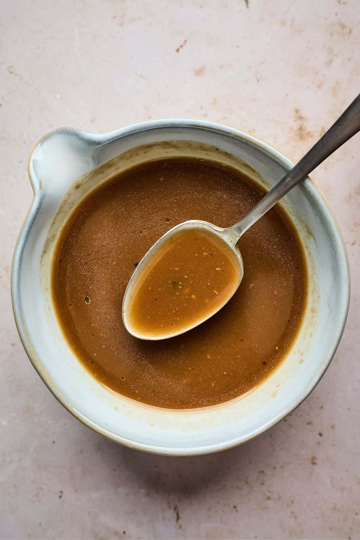 small bowl full of the best au jus recipe with a spoon scooping some sauce