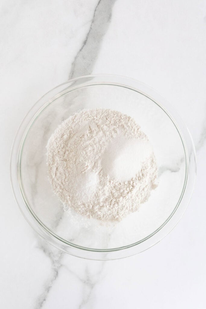 Dry biscuit ingredients in a large glass bowl on white countertop