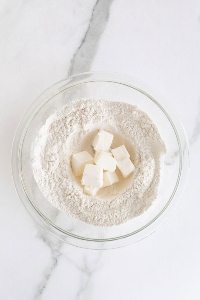 Shortening added to dry ingredients in a glass bowl on countertop