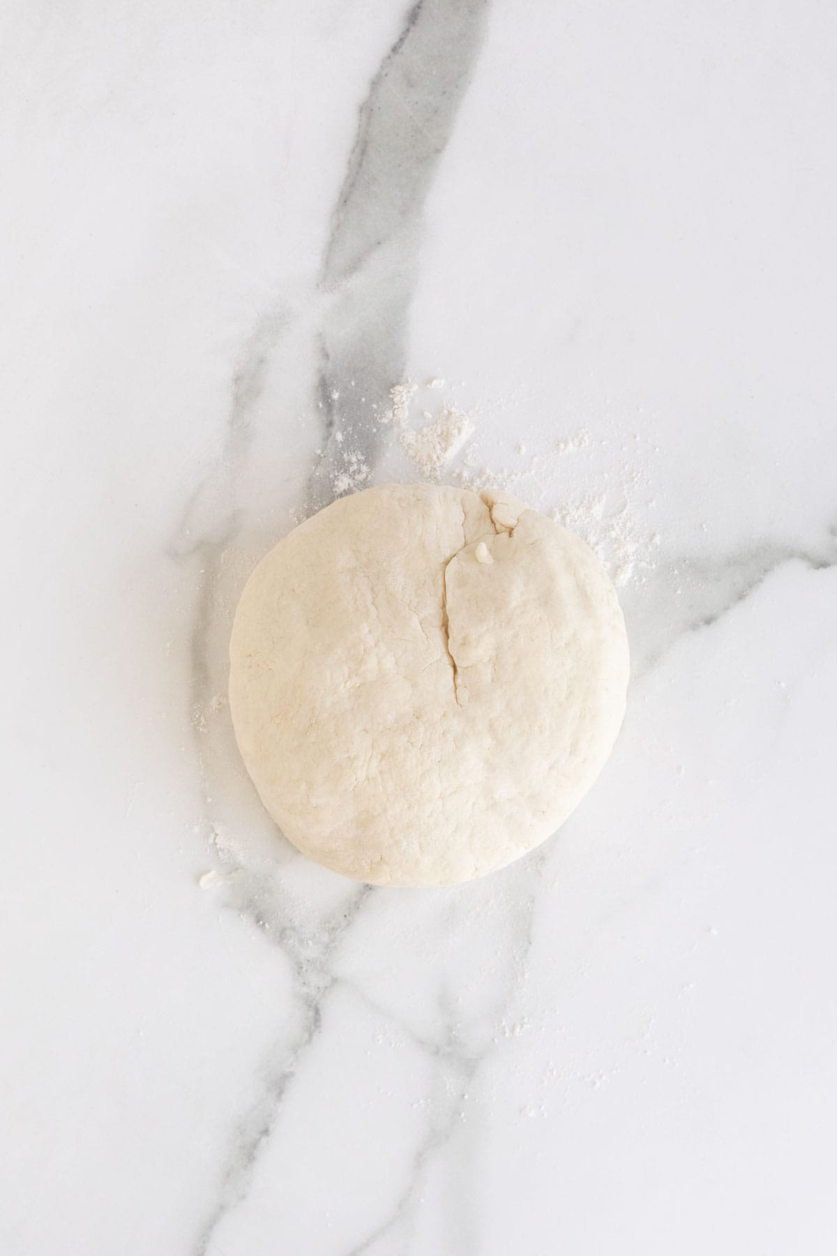 Kneaded biscuit dough on a white countertop