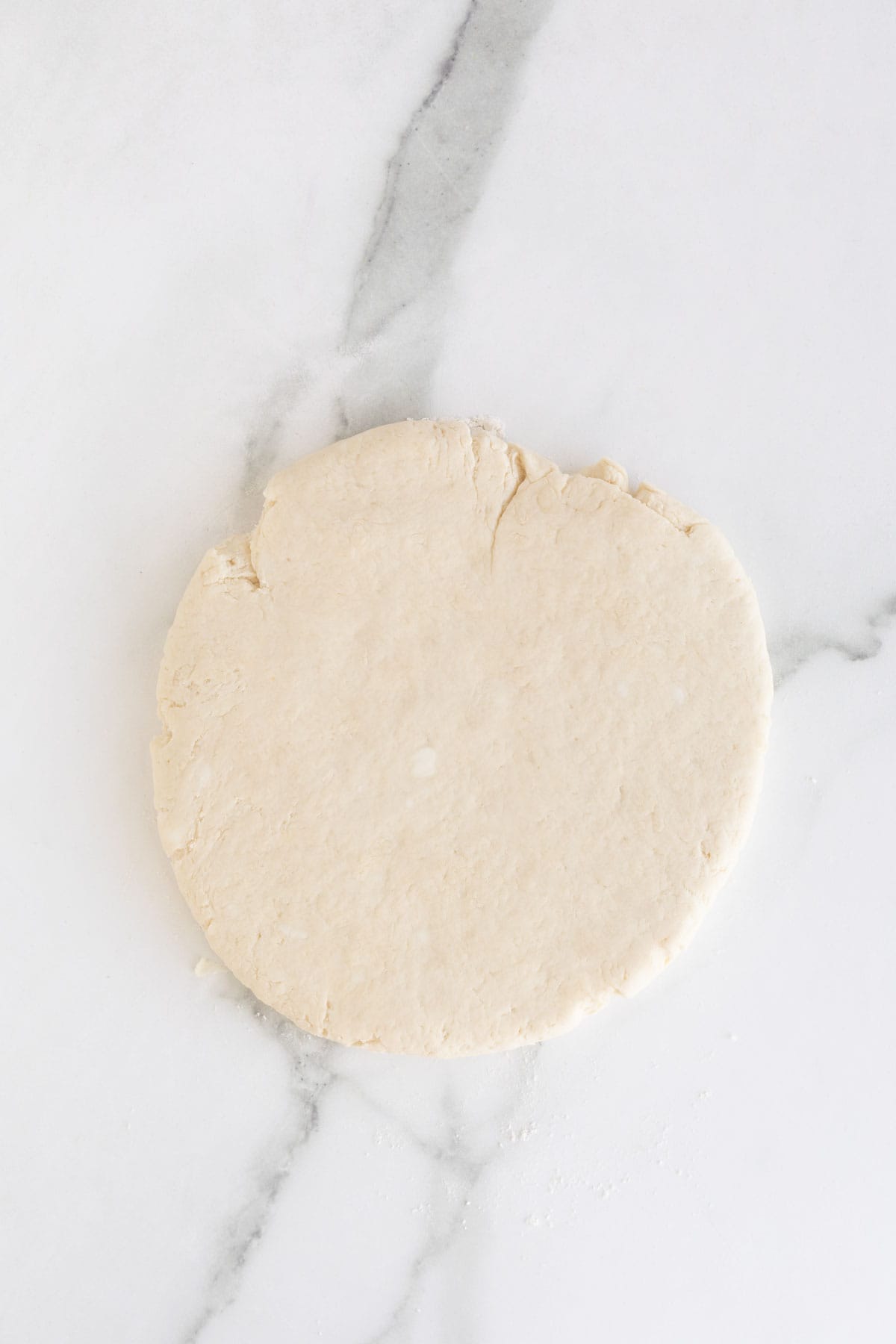 Buttermilk biscuit dough rolled out on white countertop