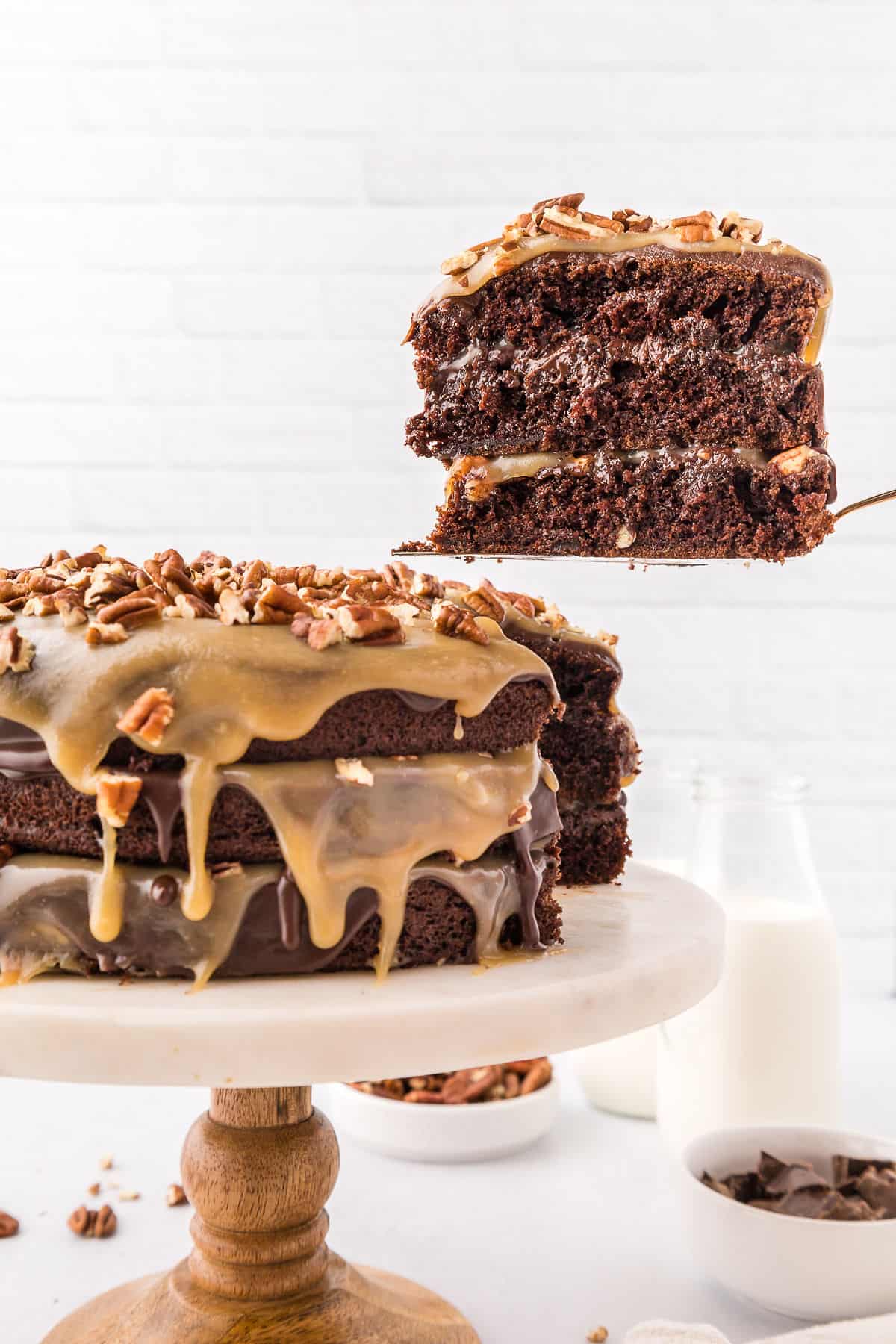 A slice of turtle chocolate cake being removed from the cake with a spatula