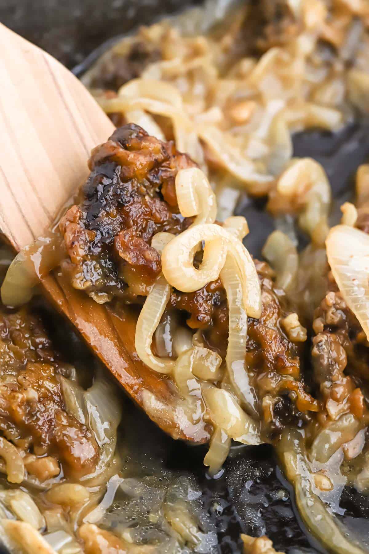 Close up of liver and onions recipe on a wooden spoon