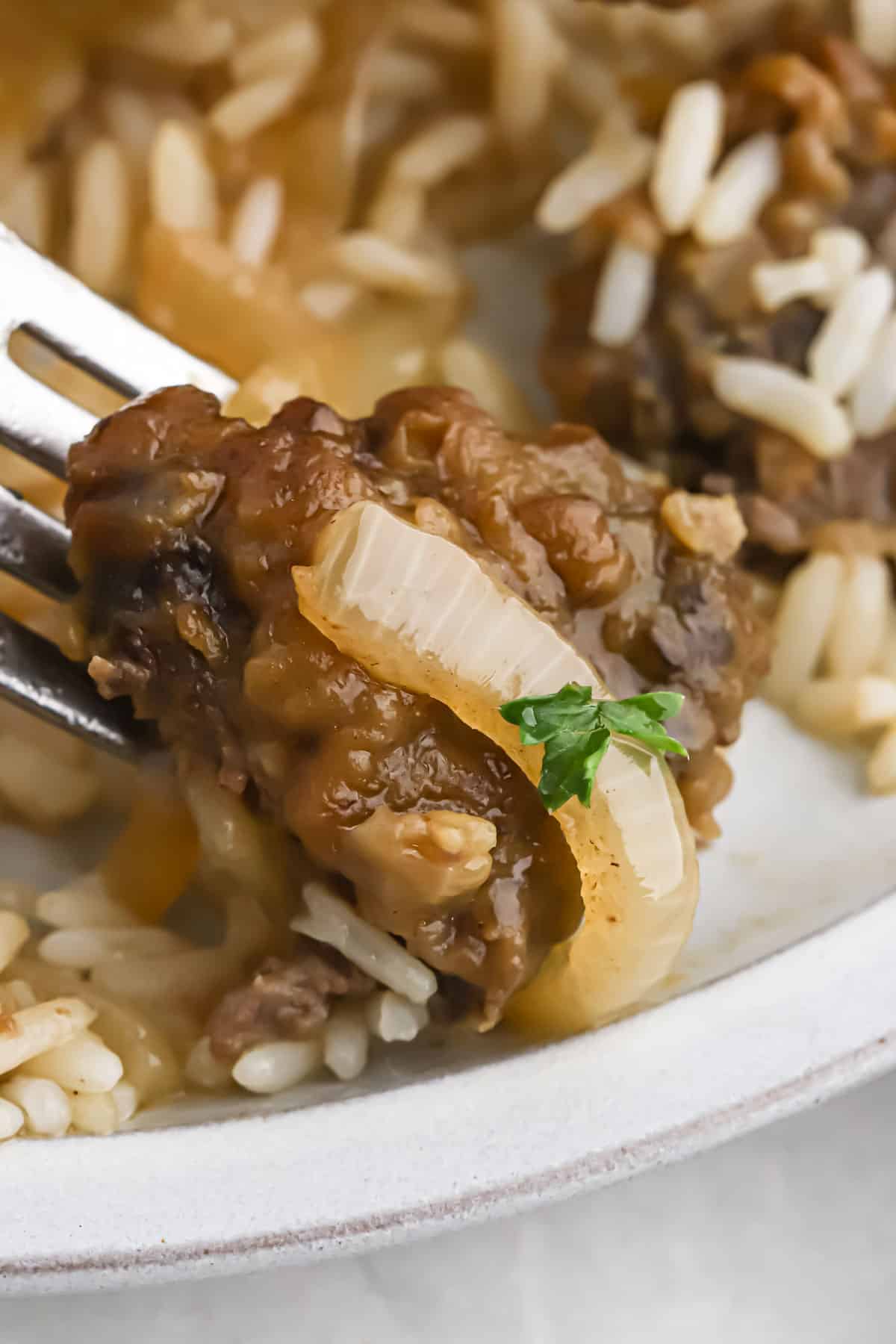 Close up of liver and onions recipe with rice being poked with a fork