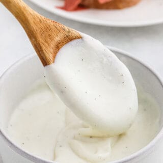 White gravy in a large white bowl with a wooden spoon