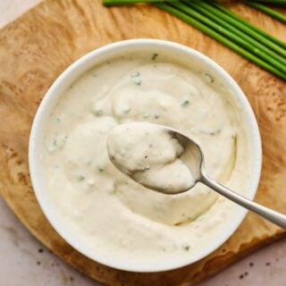 Creamy horseradish sauce recipe on a silver spoon over a bowl of horseradish sauce