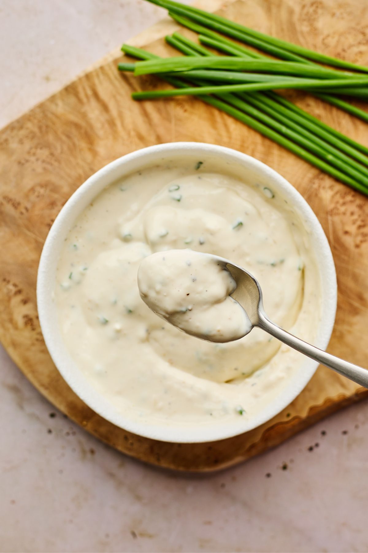 Creamy horseradish sauce recipe on a silver spoon over a bowl of horseradish sauce