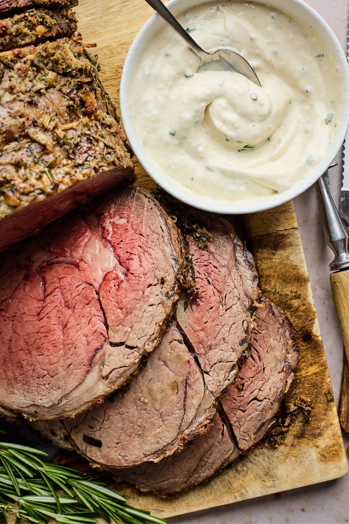 Horseradish sauce recipe served in a bowl next to slices of prime rib in a cutboard