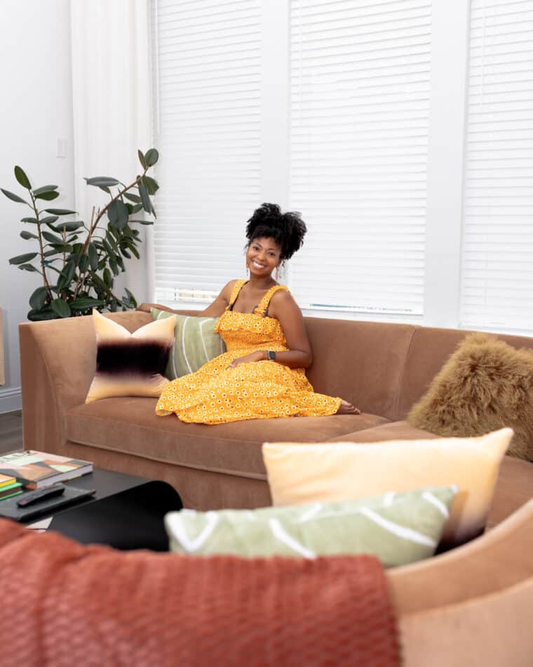 Jocelyn Delk Adams lounging on a sofa from Room and Board ready to enjoy