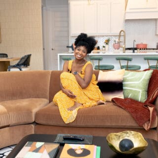 Jocelyn Delk Adams sitting on a brown sofa by Room and Board in her Texas home.