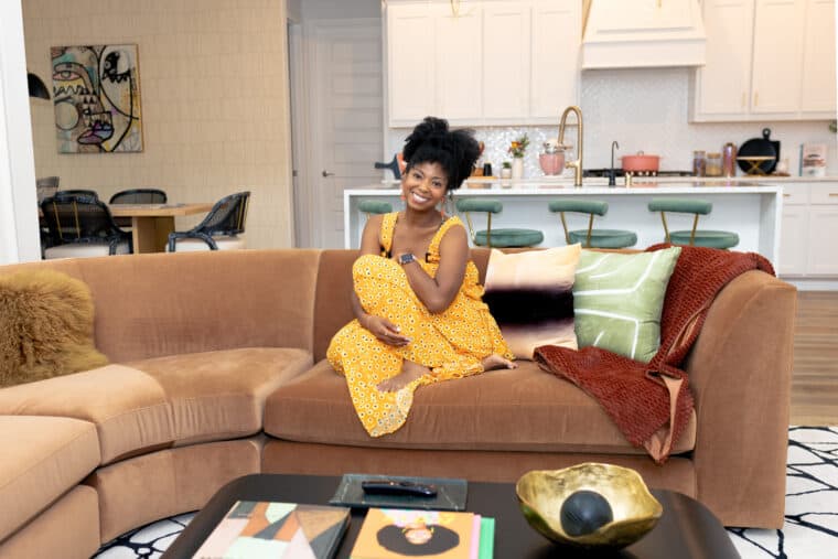 Jocelyn Delk Adams sitting on a brown sofa by Room and Board in her Texas home.