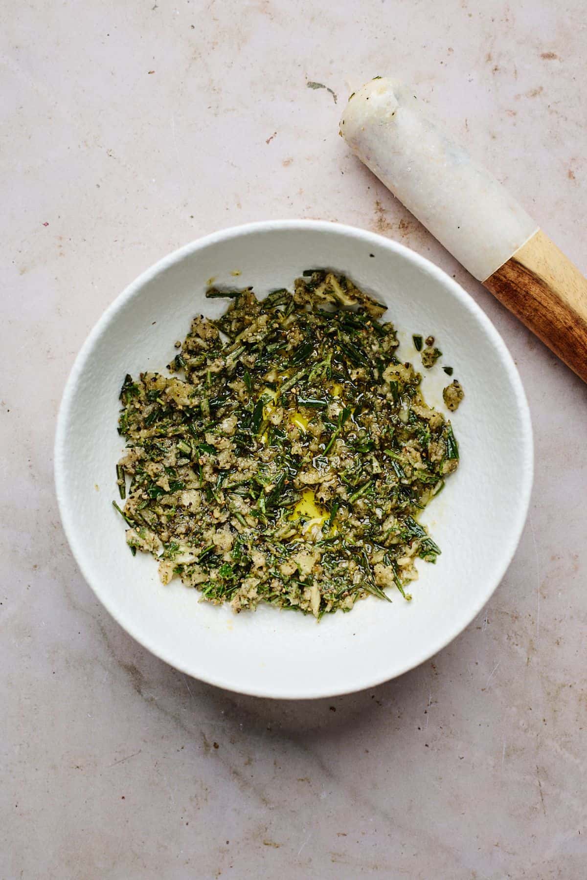 A mixed herb rub with oil in a white bowl.