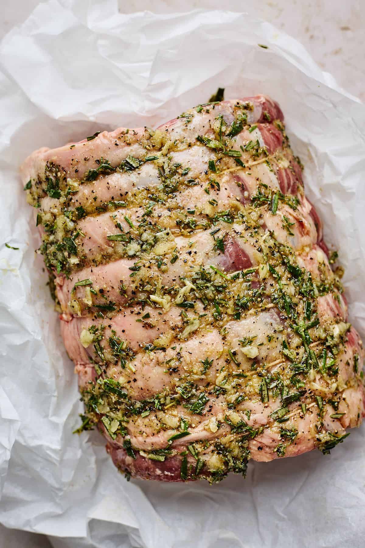 A raw prime rib roast coated with a herb rub, ready to be cooked.