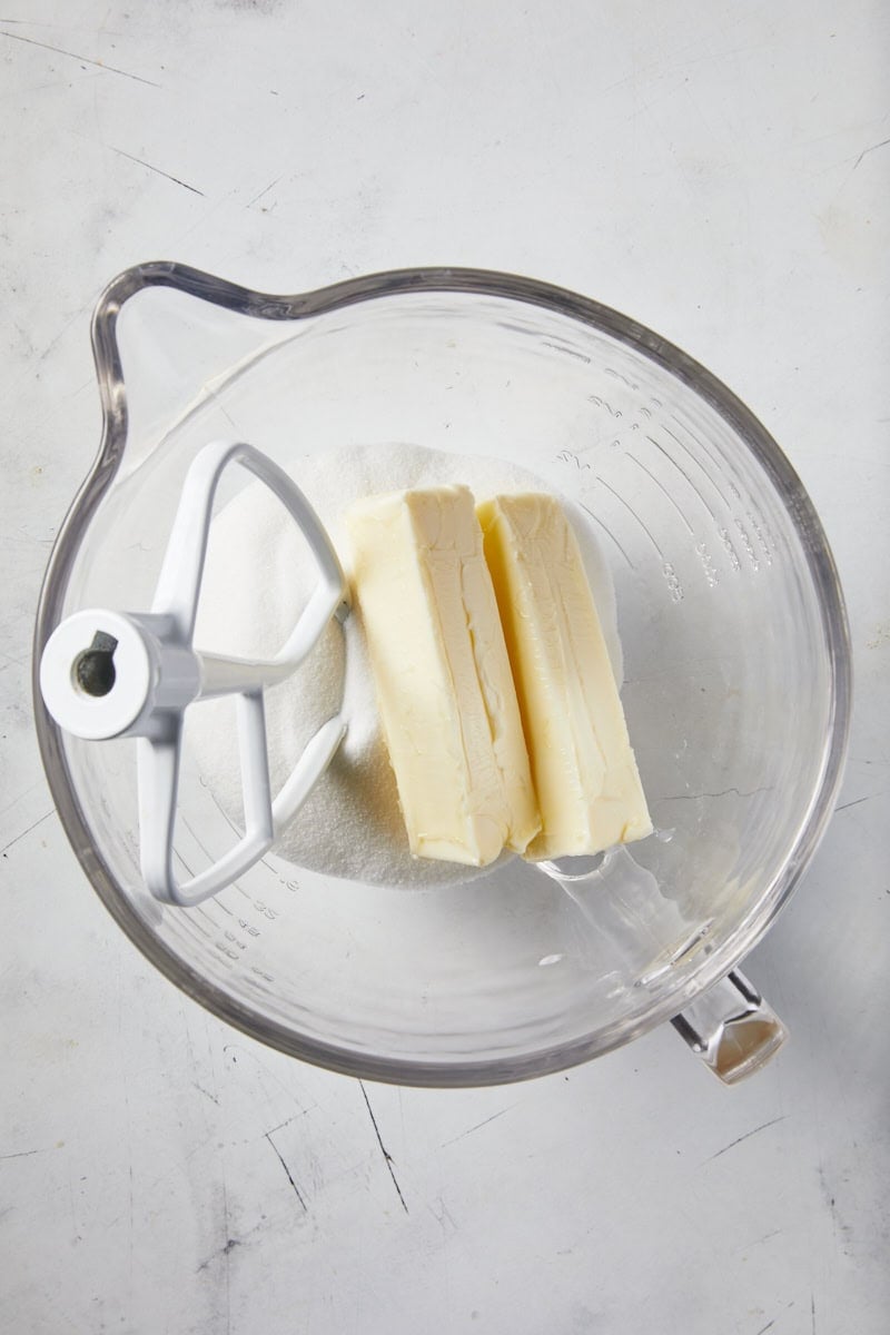 Butter and sugar in a glass stand mixer bowl on white countertop