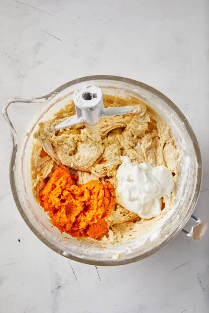 Pumpkin puree, sour cream added to a pumpkin pound cake batter in a mixing bowl