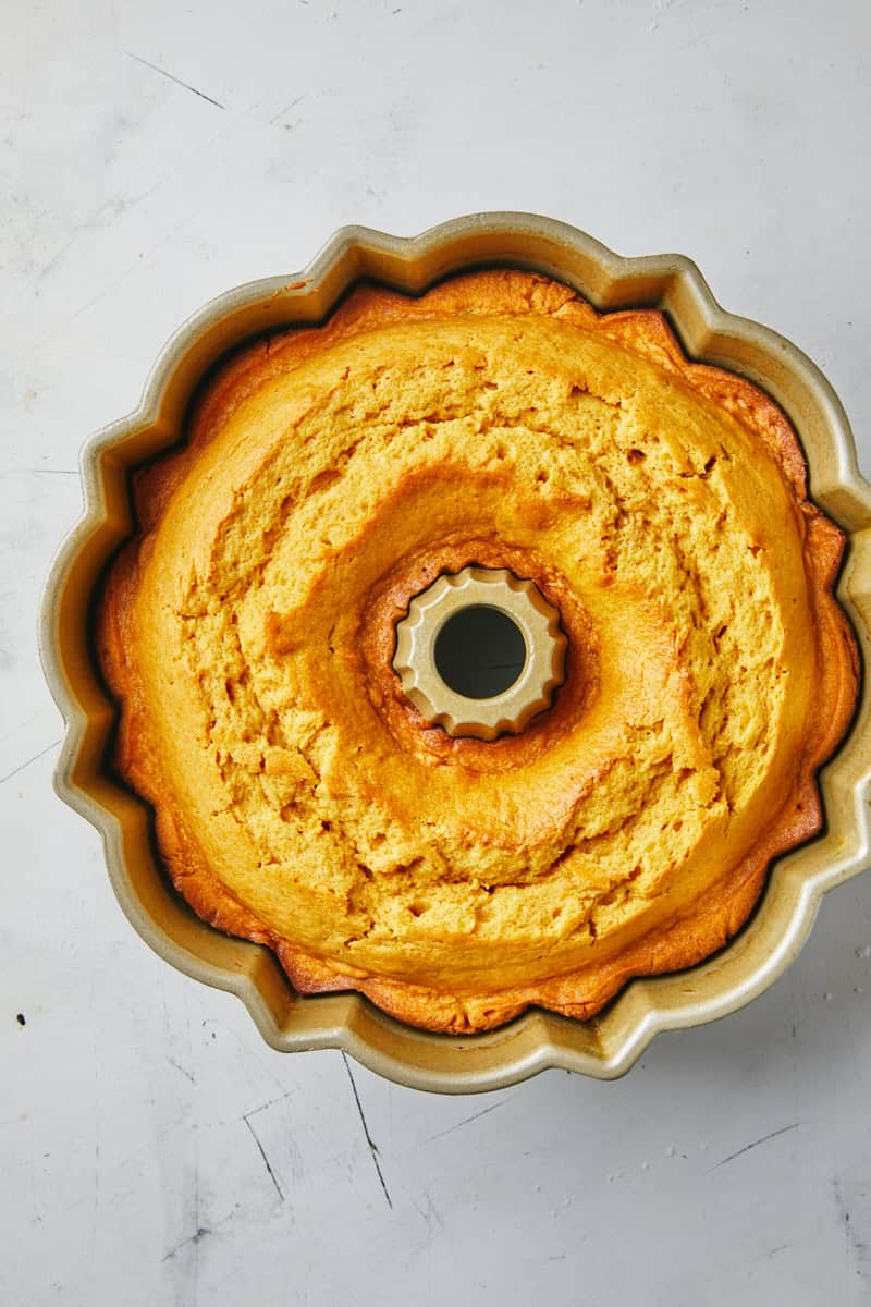 A baked pumpkin cake in a bundt pan on a white countertop