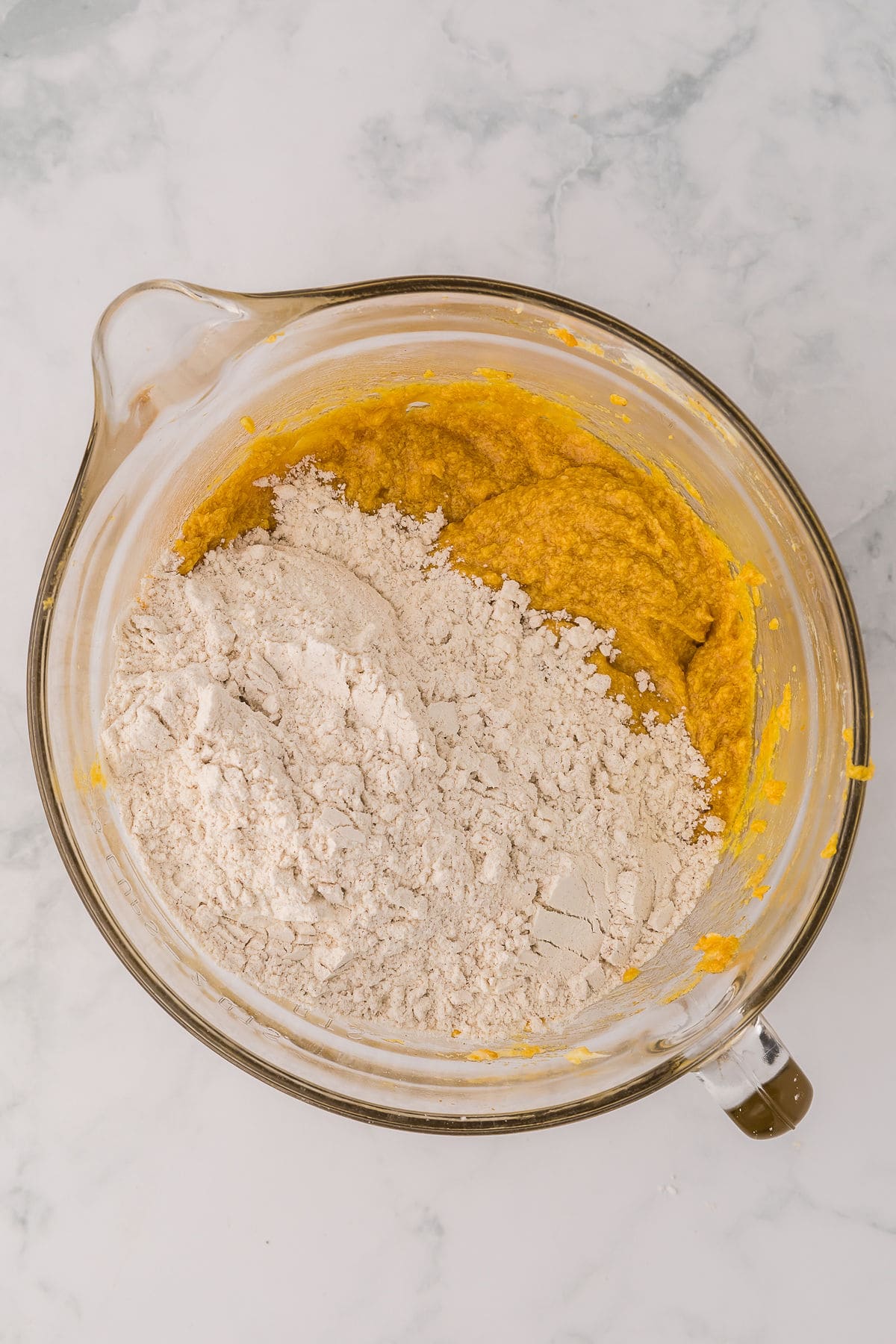 Flour mixture added to pumpkin chocolate cookie batter in mixer bowl on white background