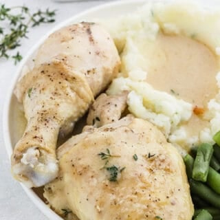 Pieces of chicken and gravy on a white plate with mashed potatoes