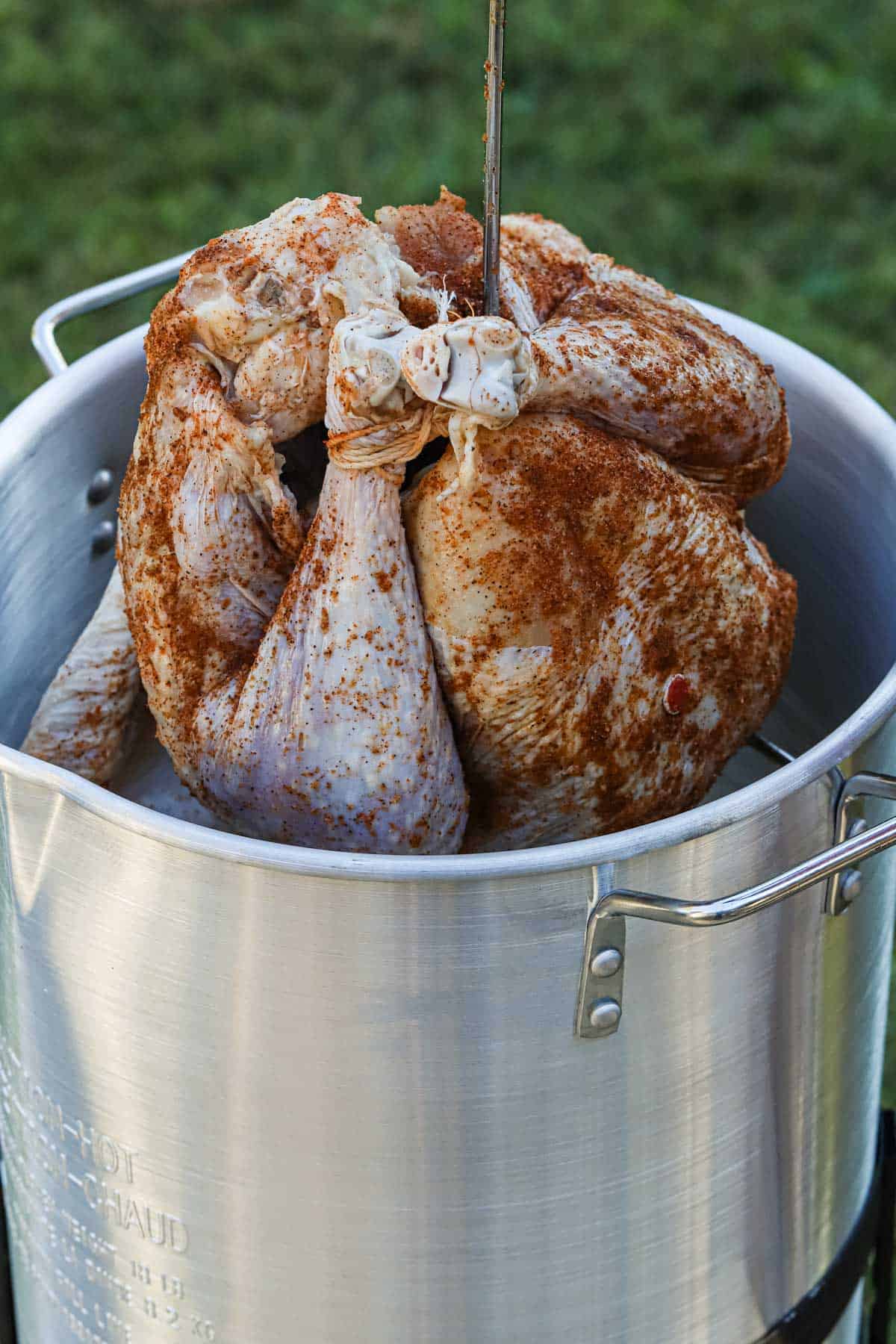 Raw turkey being lowered to a frying pot