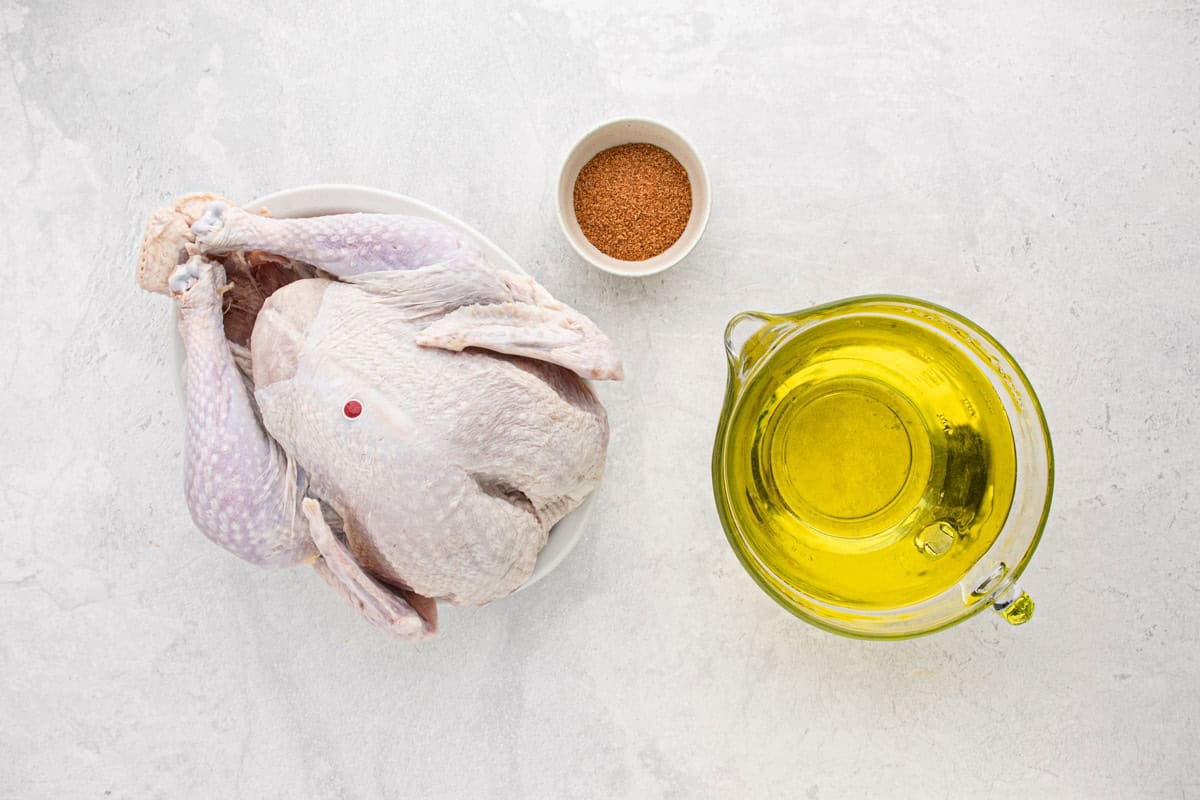 Overhead shot of ingredients for making the fried turkey on a white surface before frying