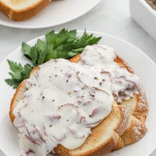 A close up of chipped beef gravy on toast on white background