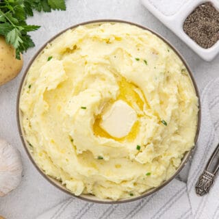 Bowl full of delicious cream Cheese Mashed Potatoes with melted butter on top