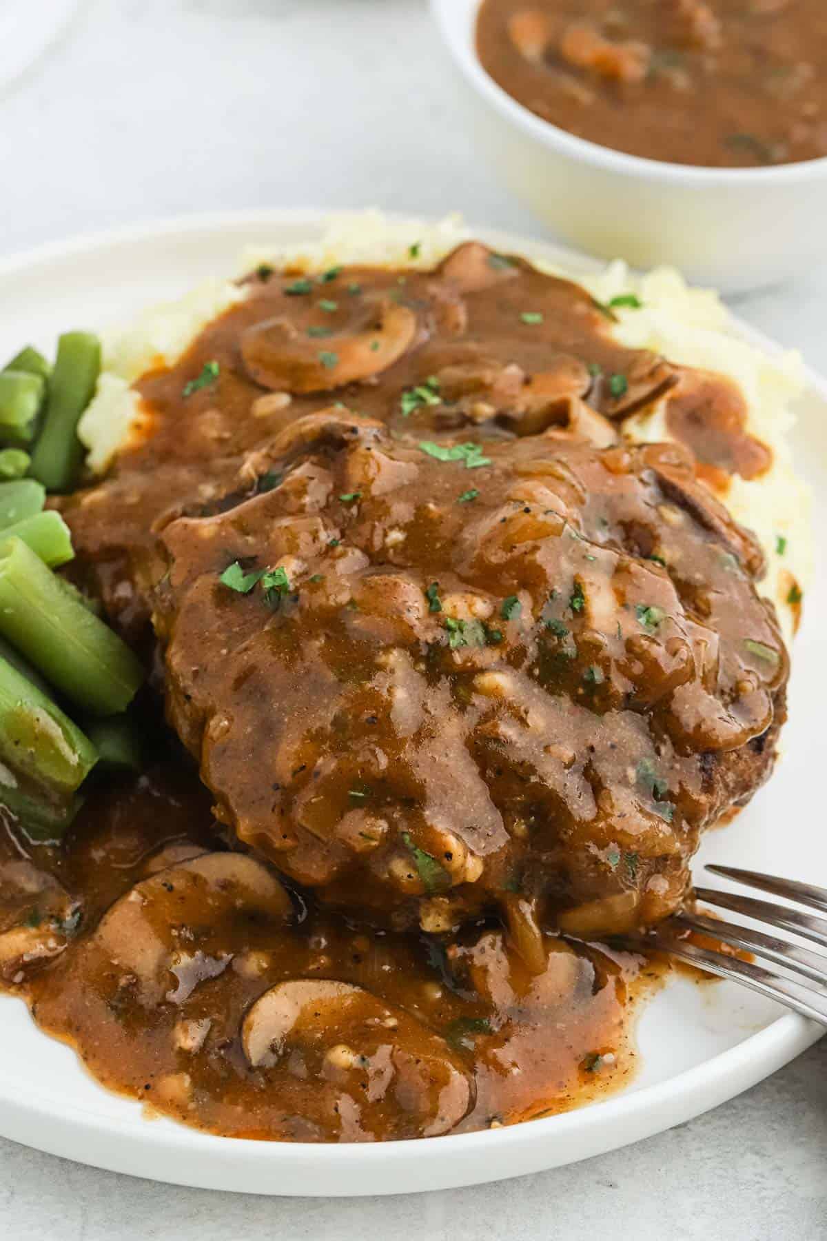 The best salisbury steak recipe with mashed potatoes and green beans topped with mushroom gravy