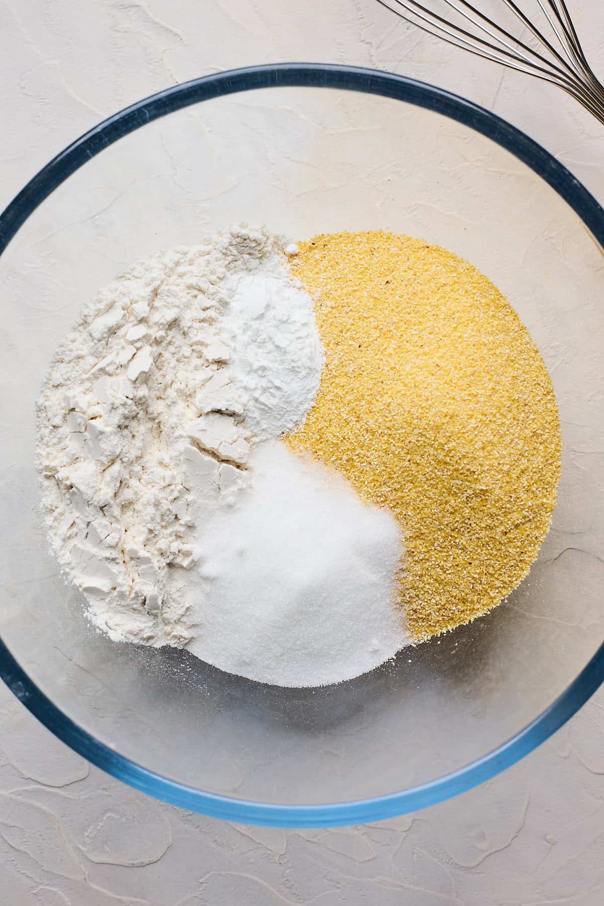 Cornmeal, flour, sugar and leavening in a clear bowl before whisking together