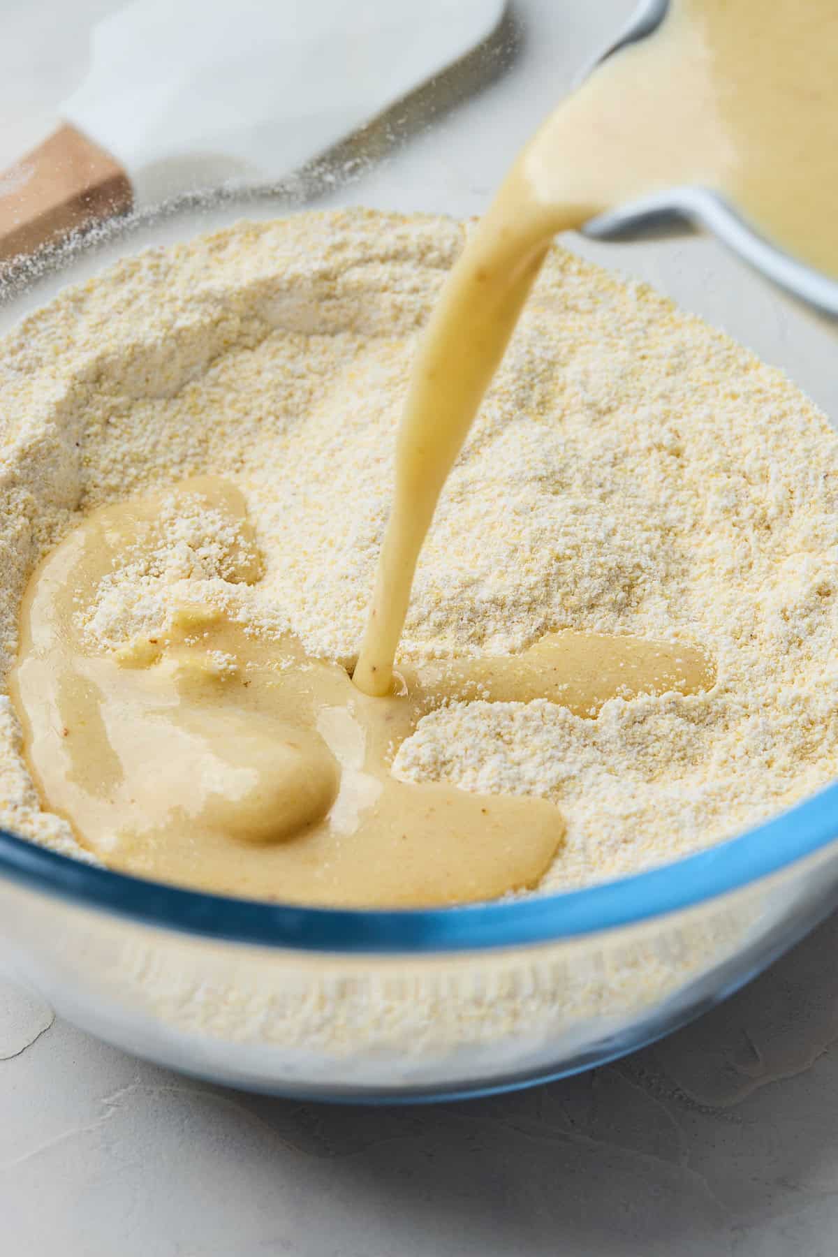 Wet mixture being added to dry mixture to make cornbread with honey