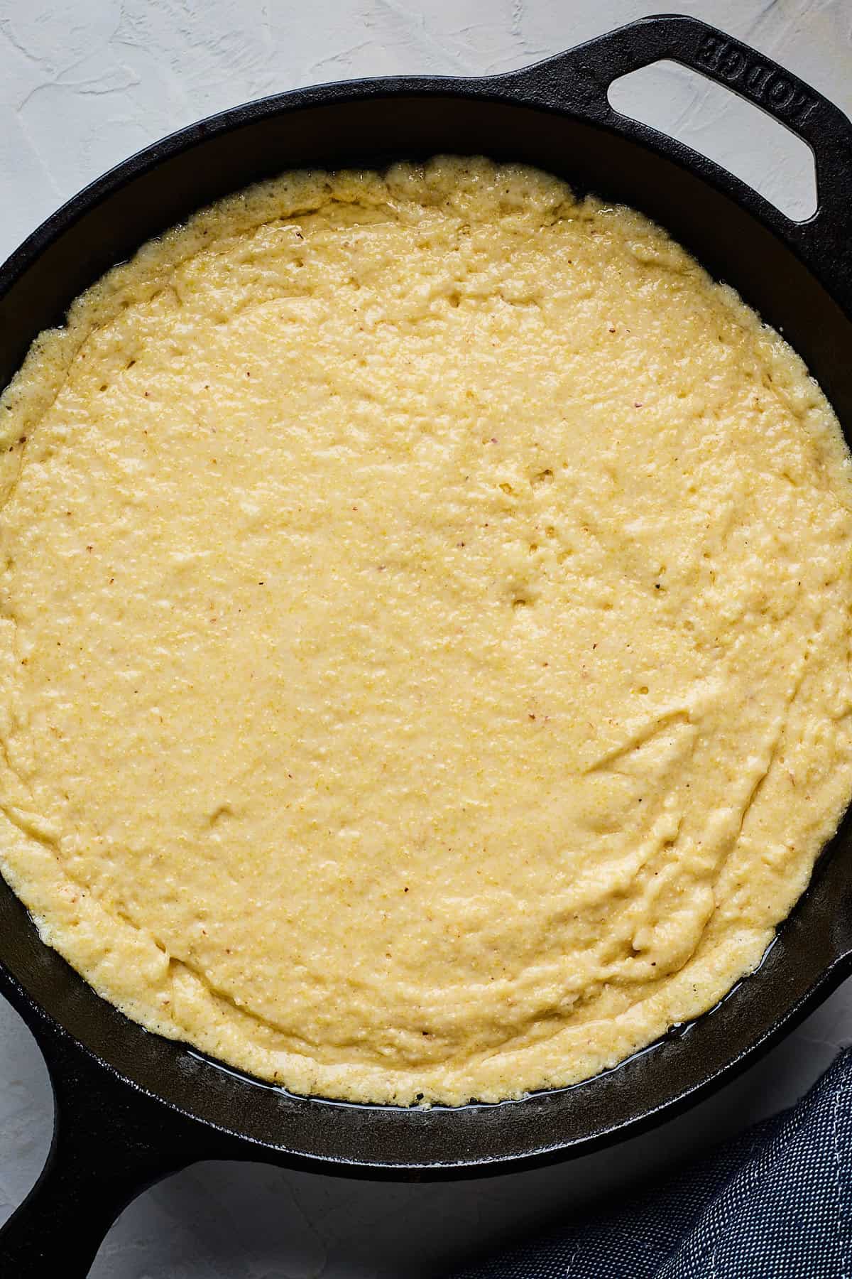 Cornbread recipe with honey batter added to a cast iron skillet before baking