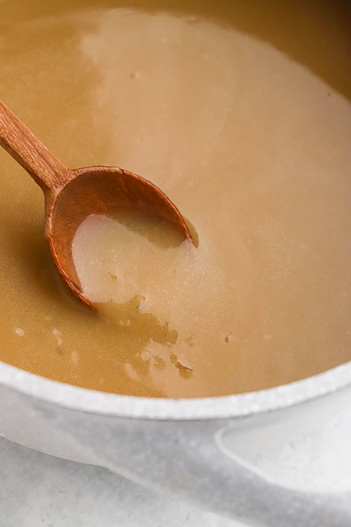 A wooden spoon in a saucepan of brown gravy