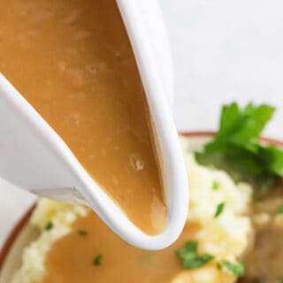 a large white gravy boat with brown gravy pouring