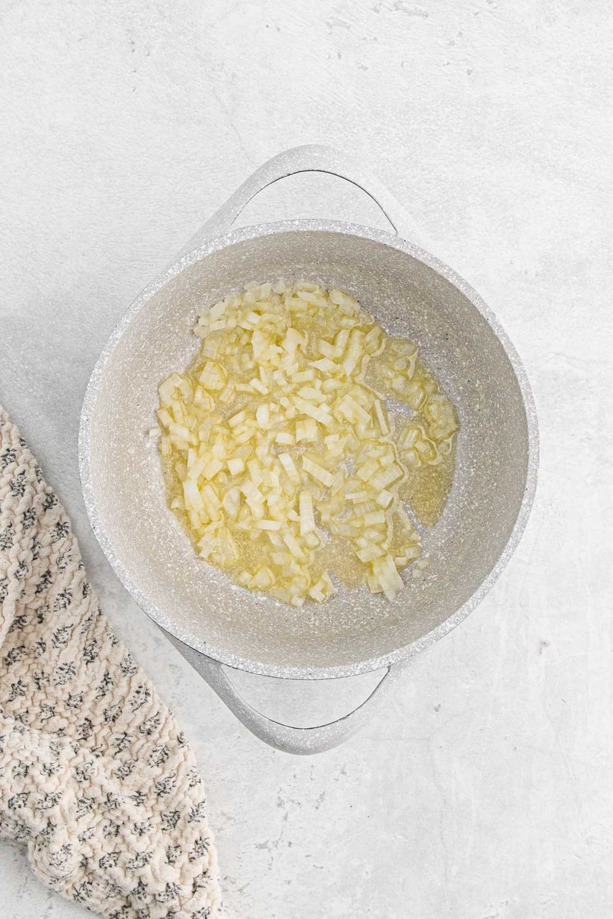 Diced onions sautéing in melted butter in a light-colored saucepan