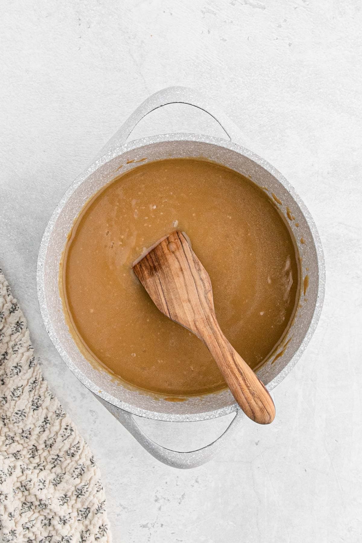 Finished brown gravy thickened and ready to serve, with a wooden spatula resting in the pot
