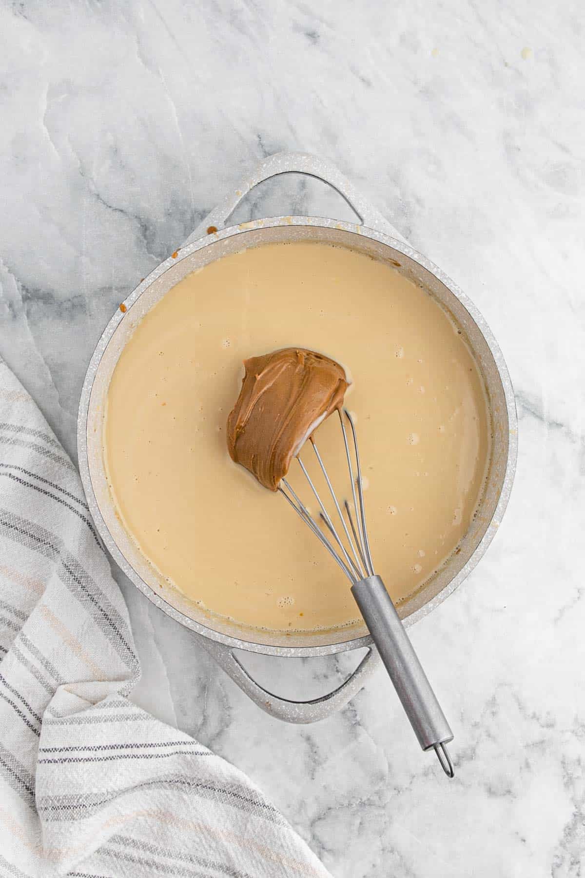 Cookie butter mixture in a saucepan with a whisk before stirring in the cookie butter
