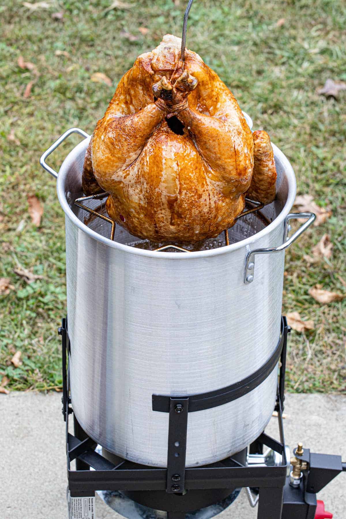 Golden and juicy fried turkey raised out of the fryer pot