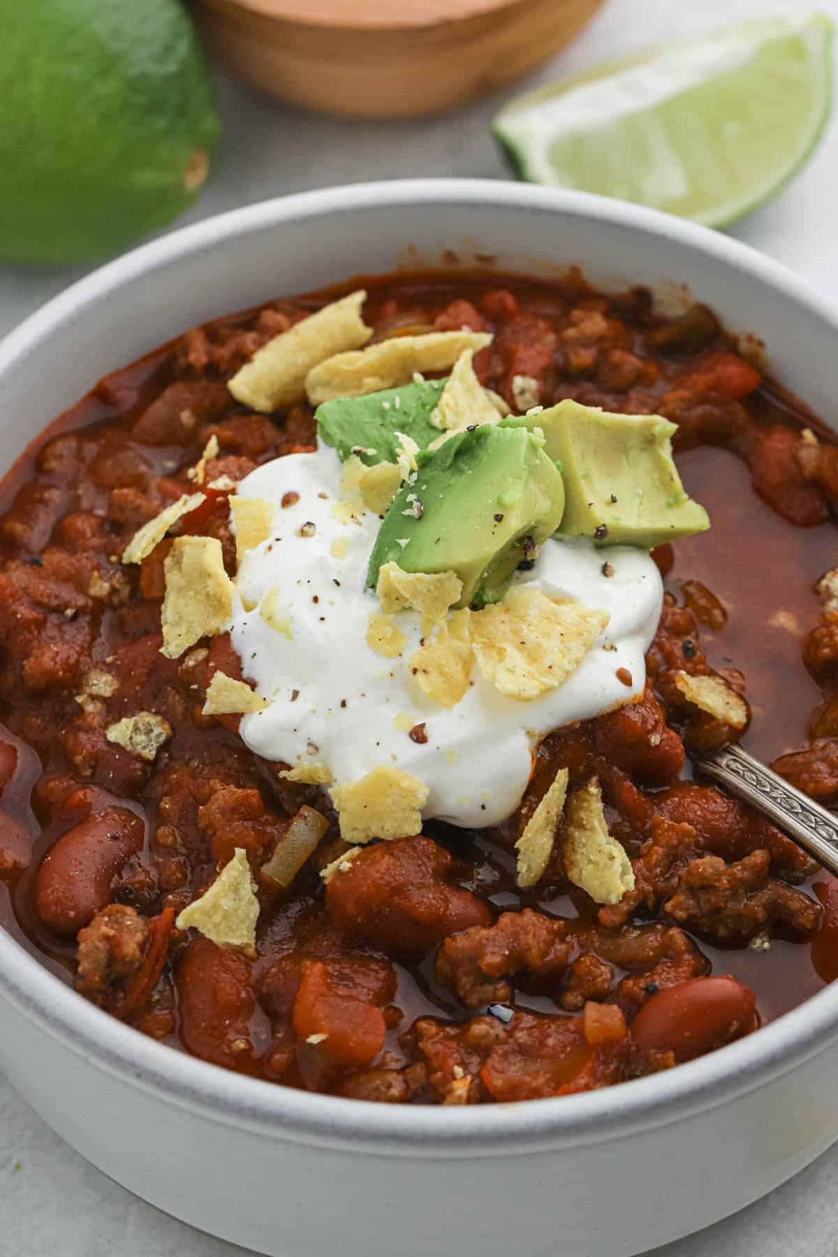 A bowl of the best chili topped with sour cream, crushed tortilla chips and avocado.