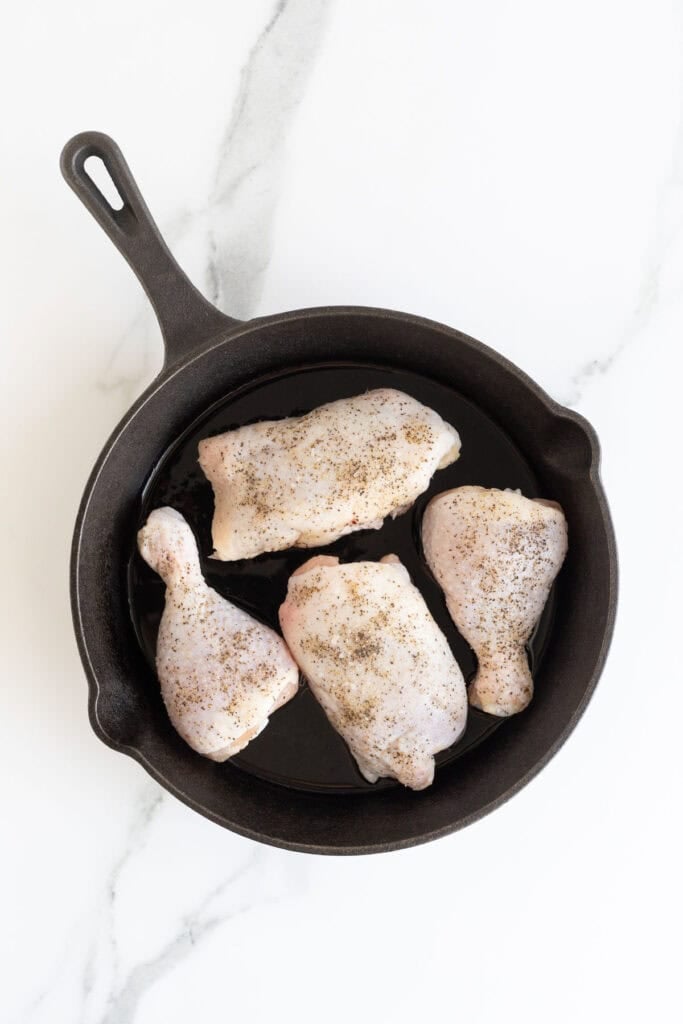 Seasoned chicken added to cast iron skillet to cook
