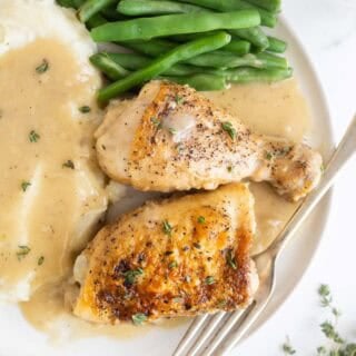 A plate with chicken and gravy, mashed potatoes and veggies ready to serve