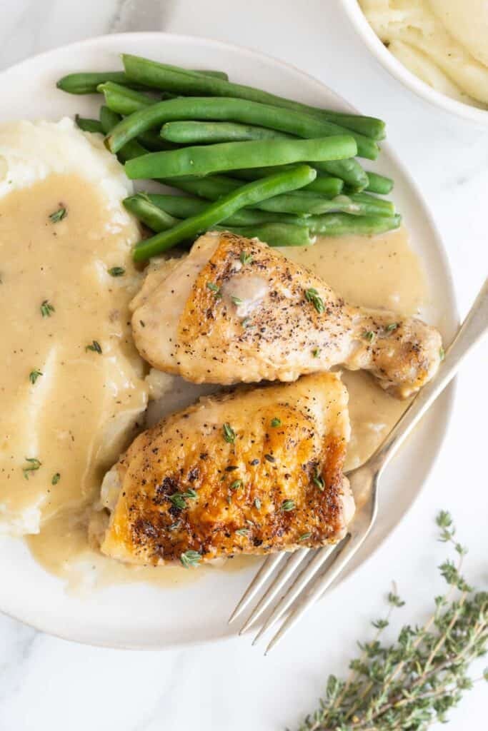 A plate with chicken and gravy, mashed potatoes and veggies ready to serve