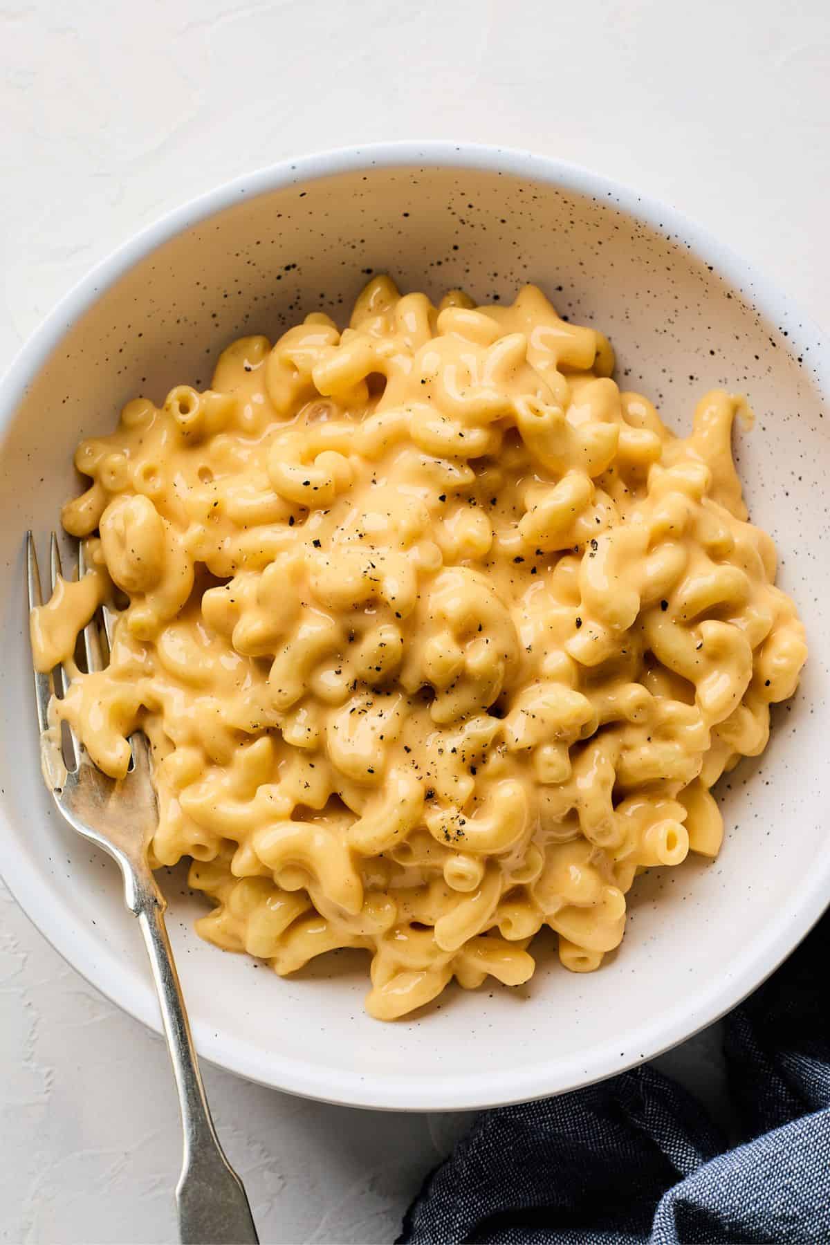 Velveeta mac and cheese sprinkled with black pepper in a white bowl with a fork