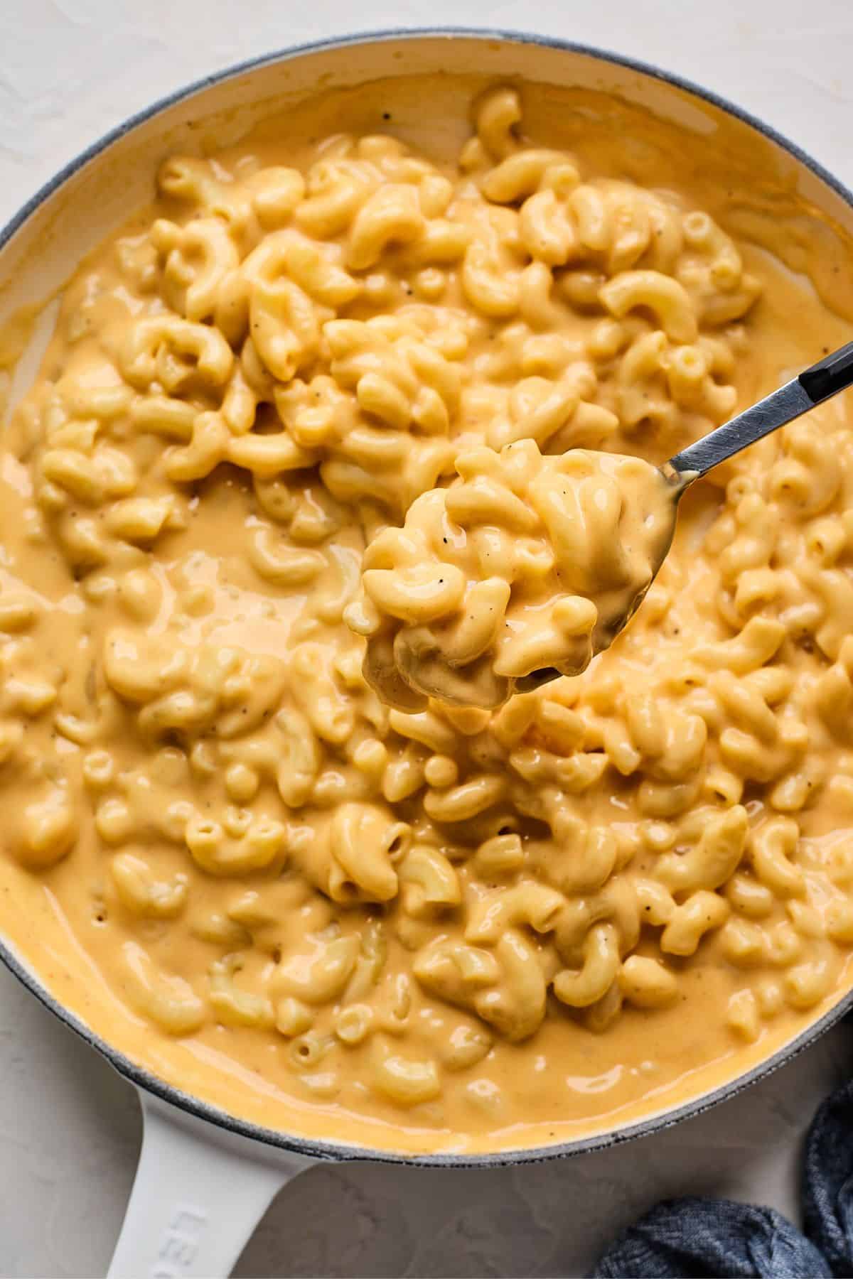 A spoon lifting a scoop of velveeta mac and cheese out of a saucepan