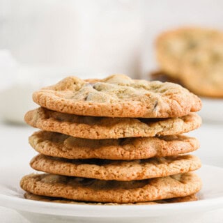 A stack of crispy chocolate chip cookies on a white plate